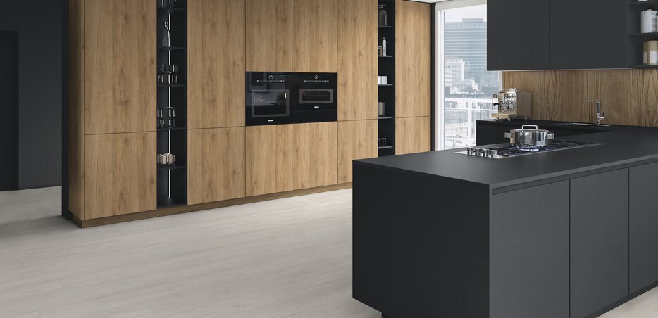 Designerküche mit schwarzer Kochinsel, Holzfronten, integrierten Elektrogeräten und modernem Stauraumkonzept in stilvollem Loft-Ambiente.