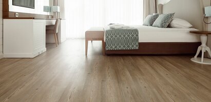 Helles Hotelzimmer mit Furnierboden und einem großen Doppelbett