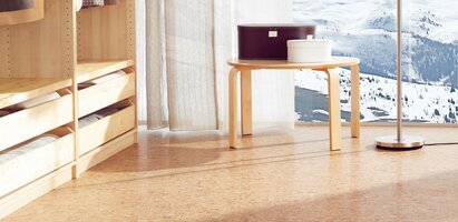 Helles Schlafzimmer mit Korkboden, einem offenen Kleiderschrank und Blick auf eine verschneite Landschaft