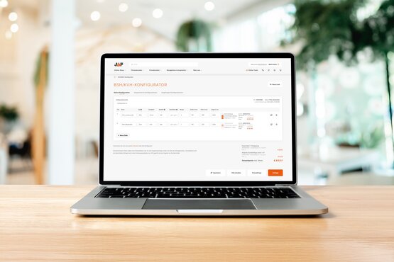 Laptop mit geöffneter JAF BSH/KVH-Konfigurator-Website auf einem Holztisch. Das digitale Planungstool für Brettschichtholz (BSH) und Konstruktionsvollholz (KVH) zeigt eine Tabelle mit Produktdetails, Maßen und Preisen.