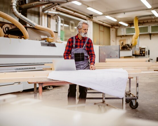 Ein Arbeiter in Schutzkleidung steht in einer modernen Produktionshalle, Symbolbild für die industrielle Holzverarbeitung im Firmenkundenbereich von JAF.