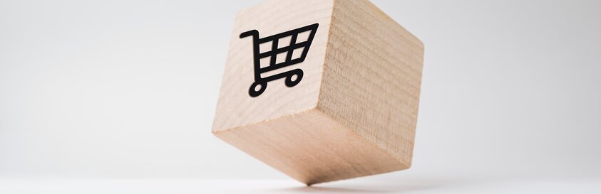 Ein kleiner Holzwürfel mit einem Einkaufswagen-Symbol steht auf einem Eck