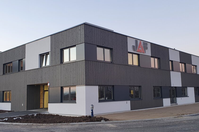 Modernes JAF Gebäude Ein modernes Bürogebäude mit grauer Holz-Fassade und Fenstern.