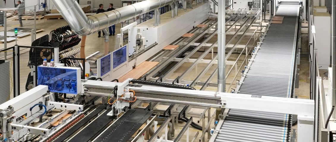 Eine moderne Produktionsanlage fertigt Holztprodukte vollautomatisch. Auf einem Förderband liegen Holzplatten, die von Maschinen verarbeitet werden. Die Szene zeigt eine industrielle Fertigung ohne menschliches Hilfe.