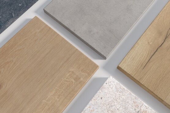 Musterstücke von Laminatplatten in Holz- und Steindekoren nebeneinander präsentiert Mehrere schmale Laminatplatten mit unterschiedlichen Dekoren – darunter Holz-, Beton- und Steinoptik – liegen nebeneinander auf einer Fläche. Die Platten wirken wie Musterstücke zur Präsentation verschiedener Oberflächenvarianten für Arbeitsplatten oder Möbelteile.