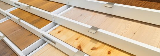 Verschiedene Bodenmuster sind in Schubladen zur Schau gestellt. Die Muster zeigen unterschiedliche Holzdekore und Oberflächenstrukturen und dienen zur Veranschaulichung von Material- und Designvarianten für Bodenbeläge.