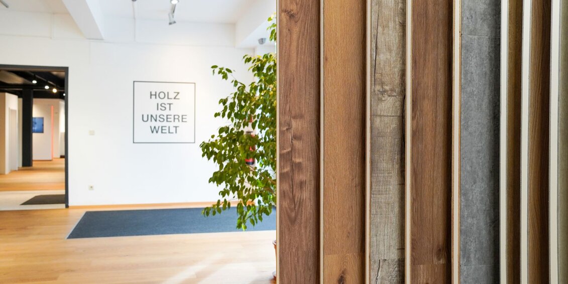 Ein moderner Schauraum mit einer Auswahl an Holz- und Dekorplatten, die ausgestellt sind. Die Umgebung ist hell und stilvoll gestaltet, mit Fokus auf Materialauswahl und Innenraumdesign.