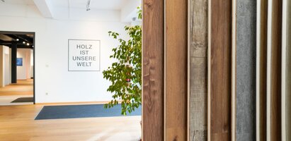 Ein moderner Schauraum mit einer Auswahl an Holz- und Dekorplatten, die ausgestellt sind. Die Umgebung ist hell und stilvoll gestaltet, mit Fokus auf Materialauswahl und Innenraumdesign.