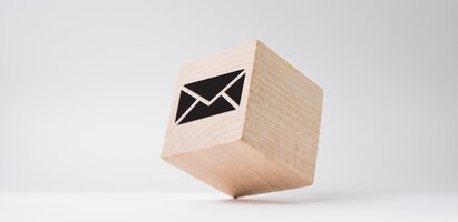 Ein kleiner Holzwürfel mit einem Brief-Symbol steht auf einem Eck