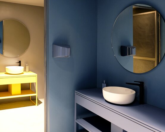 Ein schlichtes, modernes Waschbecken mit glatter weißer Oberfläche steht vor einer dunkelblauen, farblich abgestimmten Wand. Die Gestaltung ist minimalistisch und elegant, mit klaren Linien und ohne sichtbare Armaturen. Die Szene wirkt ruhig, stilvoll und hochwertig – ideal für moderne Badkonzepte.