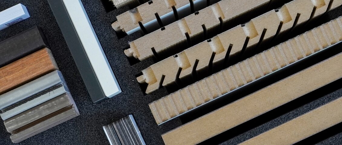 Detailreiche Nahaufnahme des geöffneten Innenraums einer Architekten-Musterbox. Zu sehen sind mehrere strukturierte Materialproben in verschiedenen Farben und Oberflächen, ordentlich in Fächern angeordnet.