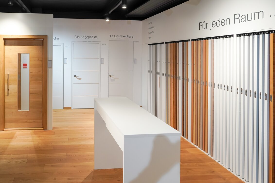 Innenaufnahme des JAF Schauraums in Stockerau. Zu sehen ist ein großzügig gestalteter Ausstellungsbereich mit verschiedenen Holz- und Plattenmaterialien, dekorativ präsentiert an Wänden und in Regalen. Die moderne, helle Raumgestaltung lädt zum Entdecken und Vergleichen von Materialien für Boden, Wand, Fassade und Möbelbau ein. Die Szene vermittelt Inspiration und professionelle Beratungskompetenz im Holz- und Baustoffbereich.