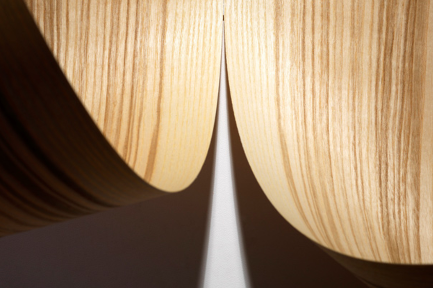 Detailaufnahme zweier gebogener Furniere Zwei gebogene Furniere mit sichtbarer Maserung liegen nebeneinander. Licht und Schatten betonen die Struktur und Form des Holzes.
