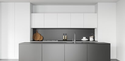 Das Bild zeigt eine moderne Küche mit weißen Oberschränken, grauen Unterschränken, schwarzer Arbeitsplatte und Rückwand. Auf der Arbeitsfläche stehen zwei Holzschneidebretter, zwei Flaschen, Geschirr sowie eine Spüle mit Wasserhahn.