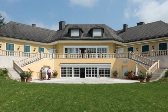 Villa mit grüner Wiese großes gelbes Gebäude mit grüner Wiese in frontaler Ansicht