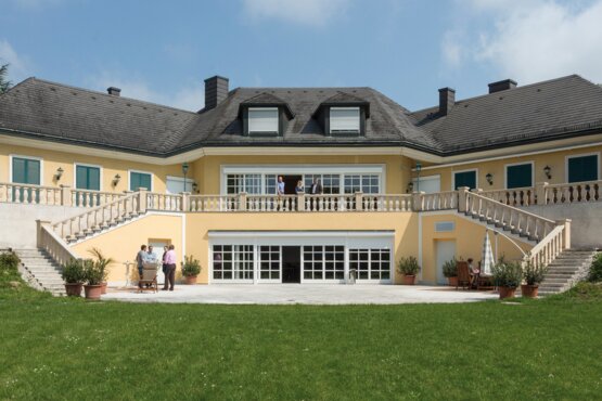 Villa mit grüner Wiese großes gelbes Gebäude mit grüner Wiese in frontaler Ansicht