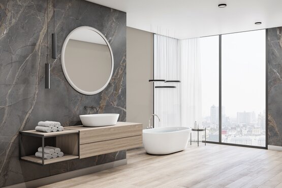 Badezimmer mit Rocko Wandpaneel | © Kronospan Modernes Badezimmer mit freistehender Wanne, marmoriertem Wandpaneel, rundem Spiegel und weitem Stadtblick durch große Fenster. | © Kronospan