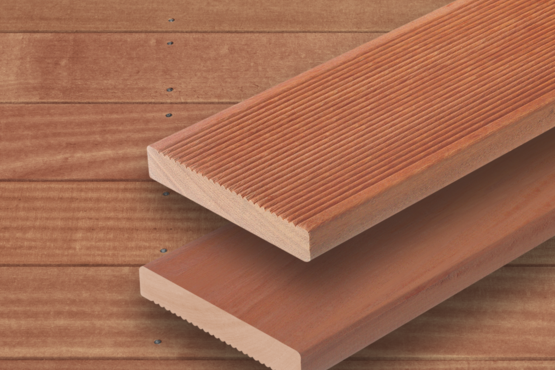 Terrassendielen aus Holz Zwei rötlich parallele Terrassendielen mit sichtbarer Maserung liegen auf einer Fläche aus ähnlichem Holz mit horizontalen Brettern im Hintergrund.