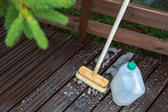 Reinigung von Holzterrasse Holzterrasse mit Schrubber und Seifenwasser während der Reinigung