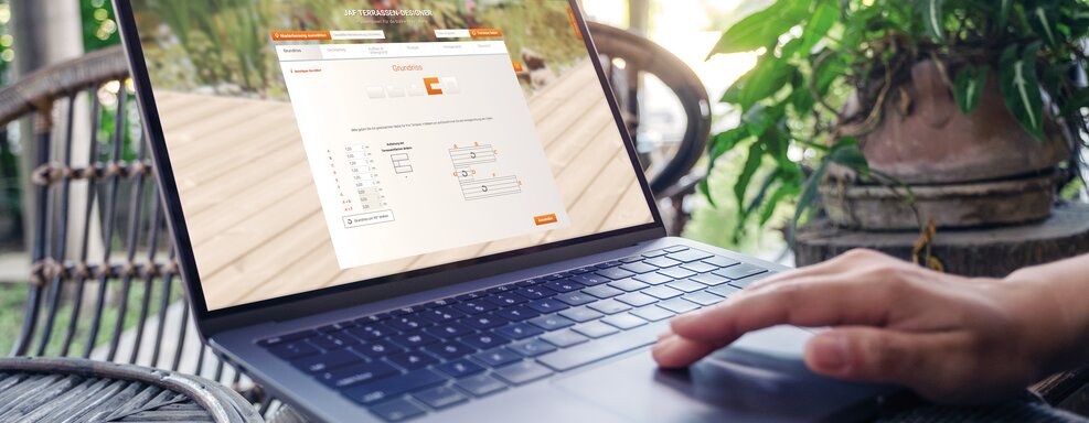 Laptop mit geöffnetem JAF Terrassendesigner auf Holzterrasse, Pflanzen im Hintergrund