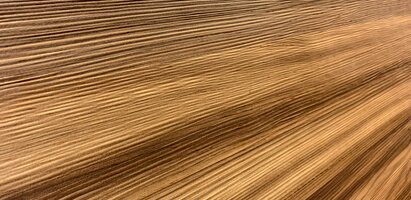 Nahaufnahme einer Holzfläche mit diagonaler Ausrichtung, sichtbarer Maserung und natürlichen Brauntönen.