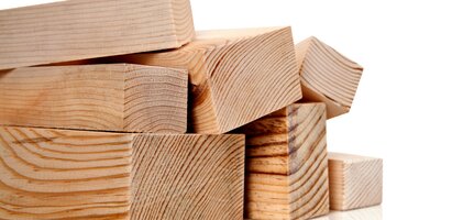 Mehrere Holzplanken unterschiedlicher Größe und Stärke liegen übereinander; die Maserung ist deutlich sichtbar, der Hintergrund ist weiß