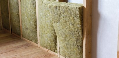 Eine Wand im Bau mit Dämmmaterial aus Mineralwolle oder Glasfaser, das zwischen Holzständern eingebracht ist. 