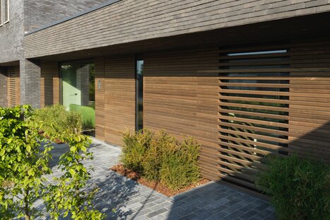Moderne horizontale Holzfassade mit Glasflächen und grauem Mauerwerk in minimalistischer Optik. | © Bloom Wellness Oudenaarde - uitv Ferraine voor Bepods - HR dr SDBR