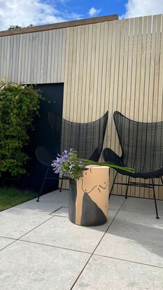 Gemütlicher Sitzplatz mit Holzlattung, Designmöbeln und Begrünung – moderne Fassadengestaltung mit Holz. | © Lalavingdesign