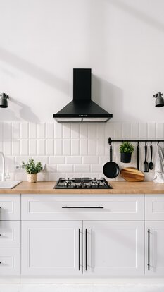Moderne Küche mit weißen Möbelfronten, Holzarbeitsplatte und stilvollem Fliesenspiegel im Industrial-Look.