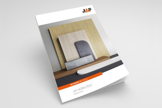 Titelseite eines Katalogs mit dem Titel „JAF MÖBELTEILE“. Zu sehen sind Holzplatten in verschiedenen Farben und Strukturen sowie ein orangefarbenes Banner mit der Aufschrift „Wohnen mit Holz“.