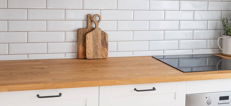 Massivholz-Arbeitsplatte in einer Küche im Landhausstil mit weißen Schränken und zwei Holzschneidebrettern