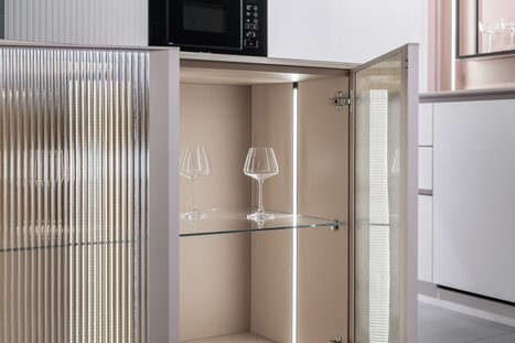 Hochschrank mit Glasfach, geriffelter Front und integrierter LED-Beleuchtung im Innenbereich