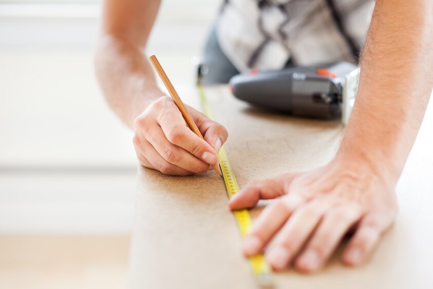 Hände markieren mit Bleistift und Maßband eine Fläche als Symbolbild für Verlegetipps bei Holz- und Parkettböden