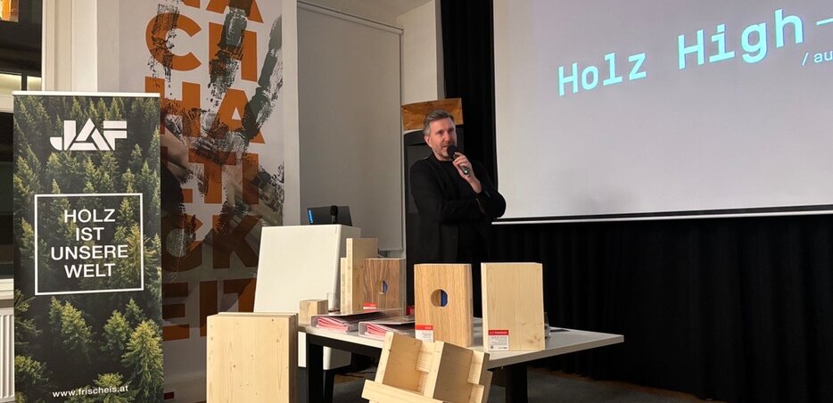 Vortrag über moderne Holzarchitektur neben Mustern verschiedener Holzbauelemente im cowerk
